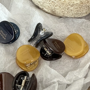 Close-up of small acetate hair claw clips with gold labels and metal spring detail