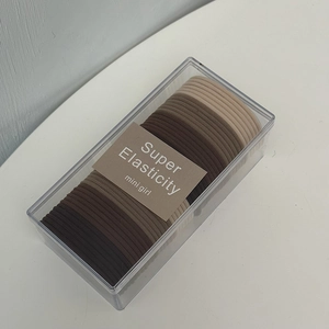 Macro view of earth-tone high-elasticity hair ties neatly stored in a clear box