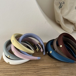 Détail de serre-têtes en satin rembourrés multicolores avec boucle dorée et étiquette