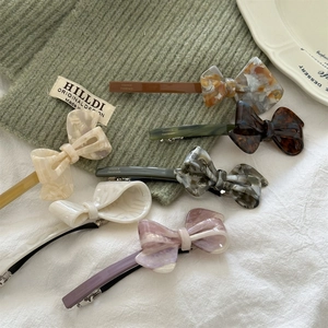 Set of six acetate bow hair clips in marble and tortoiseshell patterns with spring clips