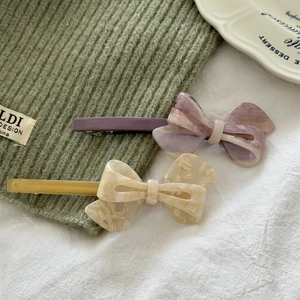 Detailed view of handmade acetate bow hair clips with purple and cream marble patterns