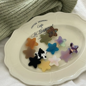 Colorful star-shaped acetate hair clips set displayed on a vintage ceramic tray