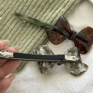 Detailed close-up of handmade acetate bow hair clips showing marble and tortoiseshell texture