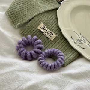 Dettaglio degli elastici a spirale viola con trama in maglia su una tovaglia bianca