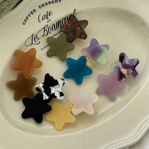 Star shaped acetate hair clips in various colors and patterns on a vintage white tray