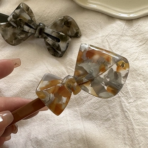 Detailed macro view of acetate bow hair clips showing elegant marble textures and spring grip