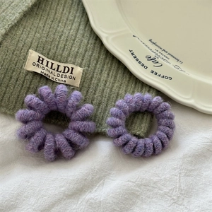 Primo piano di due elastici a spirale in peluche viola su un piatto bianco e sfondo verde bosco