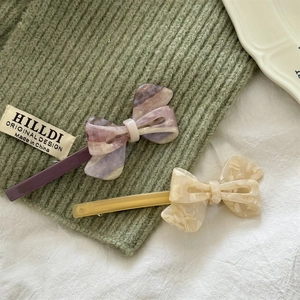 Detail of marble pattern acetate bow hair clips on olive green knit fabric