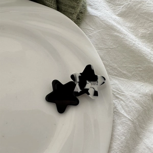 Close-up of marble pattern star hair clips set in acetate on a white ceramic plate