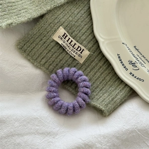Dettaglio di un elastico a spirale viola felpato su un tessuto a maglia verde morbido
