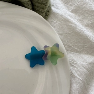 Close-up of star hair clips in blue and gradient marble acetate on a white plate