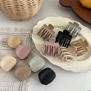 Close-up of matte hair claw clips in Morandi tones arranged on a textured fabric