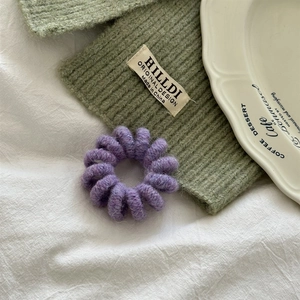 Dettaglio di un elastico per capelli a filo telefonico in maglia viola su tessuto