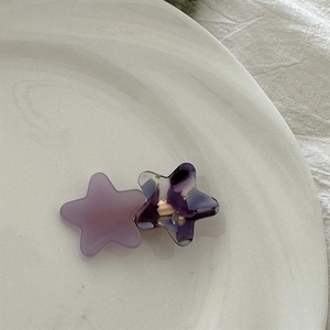 Detail of star hair clip with marble texture and purple acetate finish on a ceramic plate