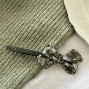 Detailed view of handmade acetate bow hair clip with gray marble texture and spring barrette