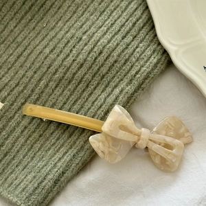 Detailed close-up of acetate bow hair clip with elegant marble texture and spring barrette