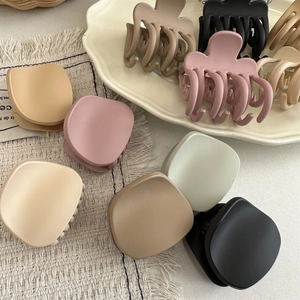 Macro shot of matte multi-color hair claws in a ceramic tray for high ponytail styling