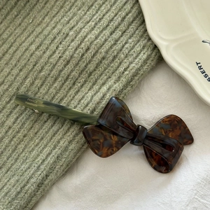 Detail of a handmade acetate bow hair clip with tortoiseshell texture on knit fabric
