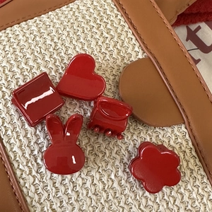 Lot de mini pinces à cheveux rouge vintage aux formes variées sur fond beige texturé
