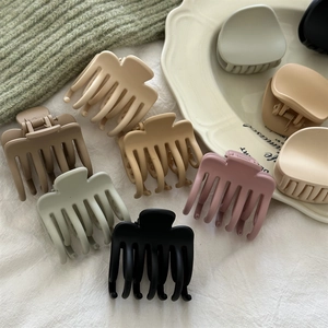Macro shot of matte shark hair clips in assorted colors on a ceramic tray