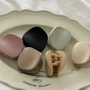 Close-up of six matte hair claws in Morandi colors displayed on a ceramic plate