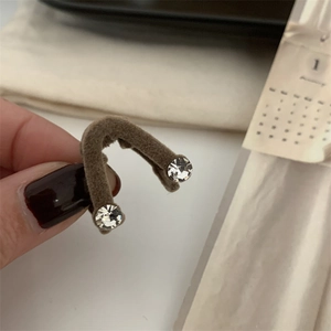 Détail d'une pince à cheveux en V floquée marron avec strass brillants à la main
