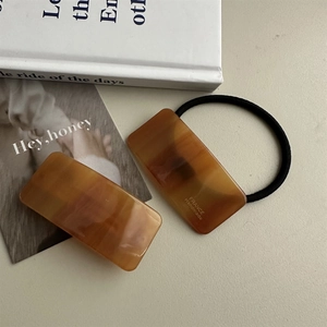 Flat lay of amber acetate hair clip set with France Handmade lettering and hair tie