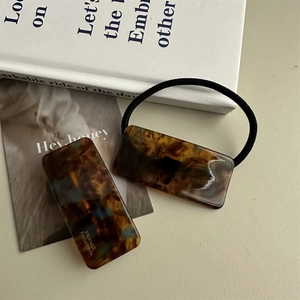 Detailed macro view of tortoiseshell acetate hair clip and hair tie set with golden engraving