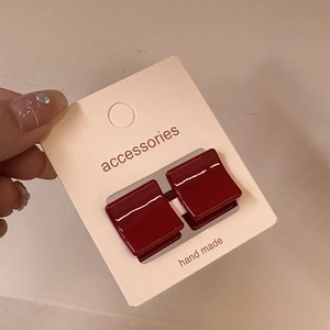 Détail de boucles d'oreilles carrées en résine rouge foncé sur carte faite main