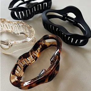 Close-up of four geometric shark hair clips in black, clear and amber tortoiseshell