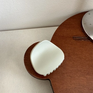 Detail view of a matte mint green hair claw clip on a rustic wooden tray setup