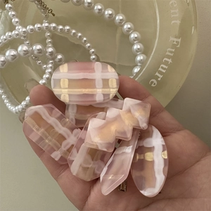 Detailed view of pink and gold resin hair clips with geometric plaid patterns