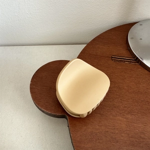 Macro shot of matte cream claw clip showing smooth finish and rounded crescent design