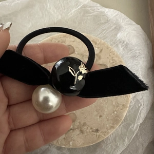 Close-up of vintage black velvet bow hair tie with camellia relief and white pearl detail