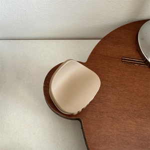 Detail of a matte beige medium-sized hair claw clip on a dark brown wooden plate