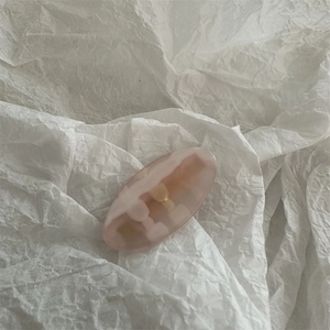 Close-up of pink marble pattern resin hair clip with gold metal spring on white paper