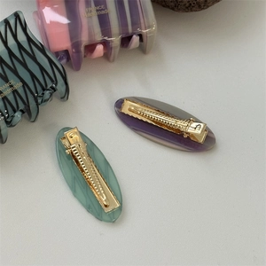 Detail of four handmade acetate hair clips including purple and cyan shark and duckbill clips