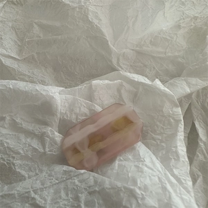 Detailed macro view of pink gradient jelly resin hair clip on white crinkle paper background