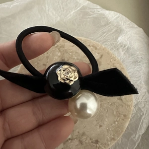 Detail of vintage camellia flower charm with pearl and black velvet bow on hair tie