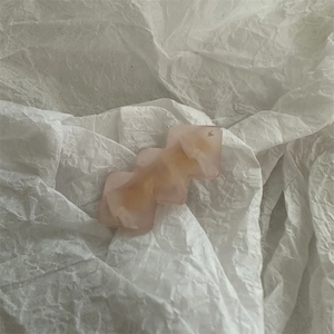 Detail view of a pink and cream resin hair clip with a jelly-like transparent finish