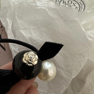 Close-up of elegant black velvet hair tie with camellia flower and pearl beads detailing
