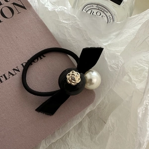 Close-up of elegant black velvet bow hair tie with camellia floral charm and white pearl