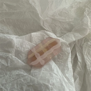 Detail of pink gradient jelly hair clip with cream checkered bow patterns on white paper