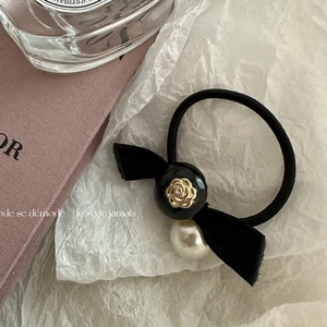 Detailed close-up of a velvet bow hair tie with camellia pearl and gold rose charms