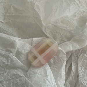 Macro detail of pink gradient grid pattern hair clip on a minimalist white texture
