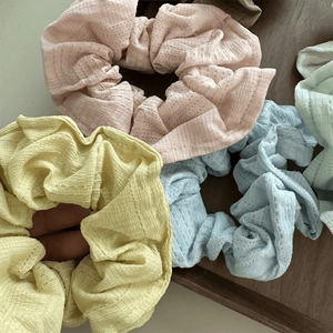 Pastel ribbed fabric hair scrunchies set in assorted colors on a wooden tray