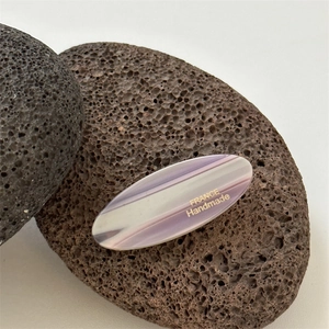Detailed macro view of purple striped acetate oval hair clip with France Handmade text