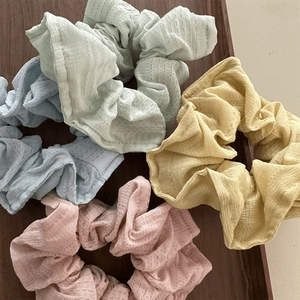 Close-up of pastel macaron-colored scrunchies with waffle texture in a wooden tray