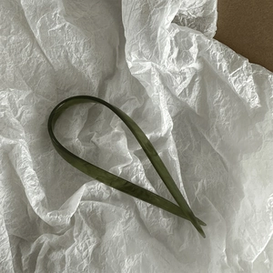 Macro shot of U-shaped marble green acetate hair stick on a white textured paper background