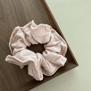 Detail of light pink scrunchie with soft ribbed fabric texture on a wooden tray